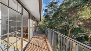 A balcony with a view of trees and a building with large windows.