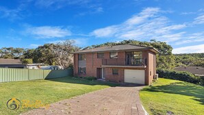 A two-story brick house with a balcony, a garage, and a well-maintained lawn.