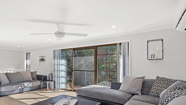 A modern living room with two grey sofas, a coffee table, and a ceiling fan.
