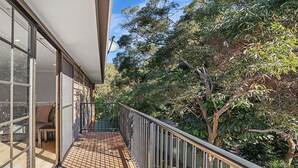A balcony with a view of trees and a building with large windows. - Amaroo Cres No 20 Fingal Bay Holiday Home (Fingal Bay)
