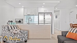 Una cocina moderna con armarios blancos, un refrigerador de acero inoxidable y un microondas integrado.
