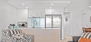 Una cucina moderna con mobili bianchi, un frigorifero in acciaio inossidabile e un forno a microonde integrato.