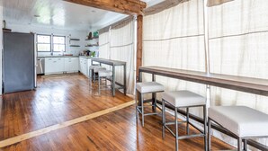 A spacious kitchen with wooden floors, a dining area with bar stools, and a view of the outdoors. - HISTORIC DOWNTOWN LOFT (Sevierville)