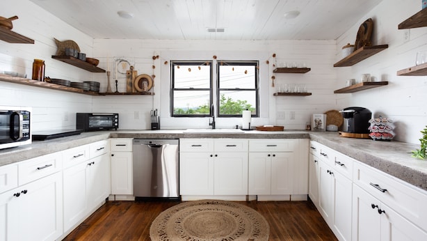 A kitchen with white cabinetry, wooden floors, and a central island with a sink and dishwasher. - HISTORIC DOWNTOWN LOFT (Sevierville)