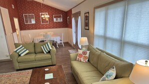 Ein Wohnzimmer mit zwei grünen Sofas, einem Holztisch und einem gemusterten Teppich.