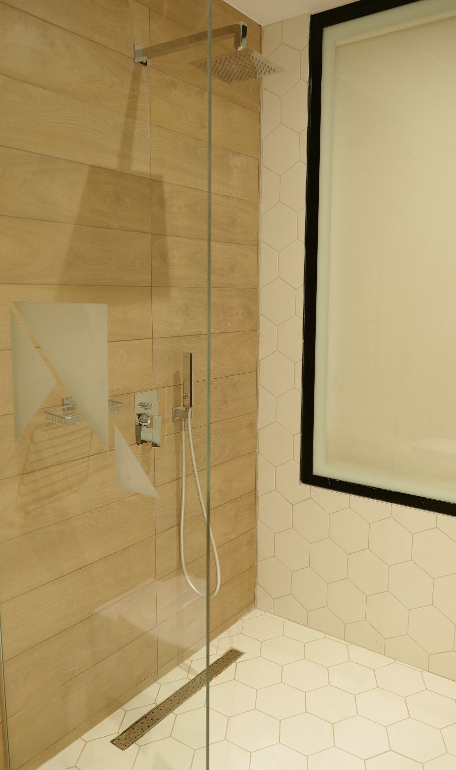 A modern shower with a glass door, a rain showerhead, and a control panel.