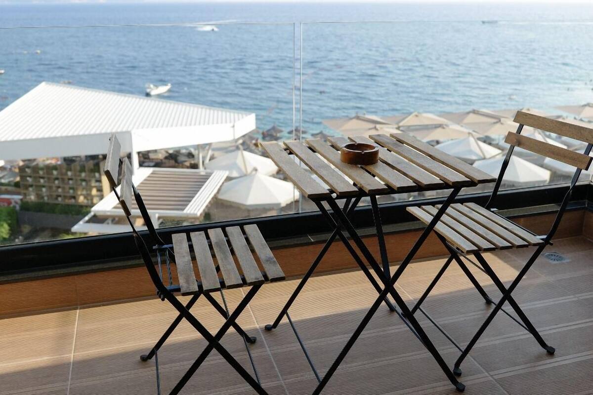 A balcony with a table and chairs overlooking the sea.