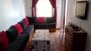 Een woonkamer met een bank, een salontafel, een televisie en een dressoir.