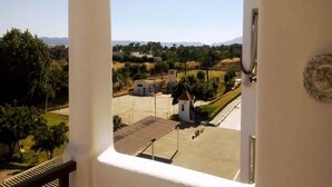 Blick von einem Balkon auf einen Parkplatz mit einem kleinen Gebäude und Bäumen.