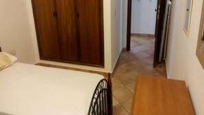 Ein Schlafzimmer mit einem Bett, einem Holzschrank und einem kleinen Holztisch.
