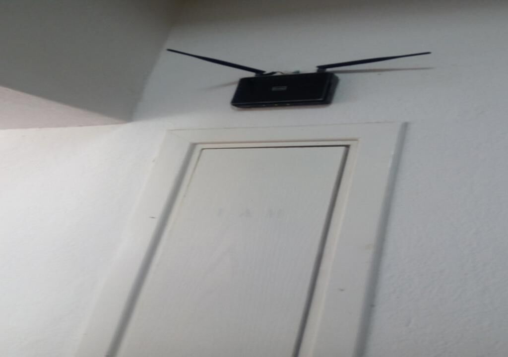 A white door with a black device mounted on the wall above it.