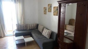 A living room with a sectional sofa, a wooden cabinet, and a mirror. - Residence Smir Park Beach 1672 (Mdiq)