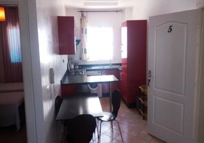 A compact kitchen with a dining area, a washing machine, and a door marked with the number 5.