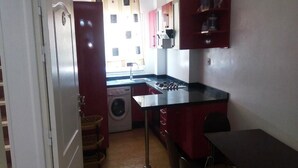 A compact kitchen with a sink, stove, and a washing machine. - Residence Smir Park Beach 1673 (Mdiq)