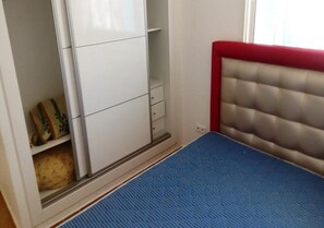 A bedroom with a bed, a wardrobe, and a red headboard.