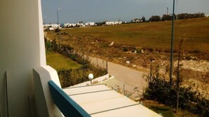 Vista desde un balcón sobre una zona de construcción con una carretera y edificios a lo lejos.