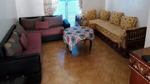 Una sala de estar con un sofá, una mesita y un tapete estampado.