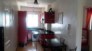 Cocina compacta con comedor, lavadora y un armario rojo.