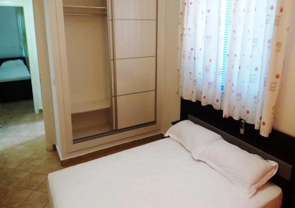 A bedroom with a bed, a wardrobe, and a window with curtains.
