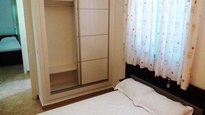 Une chambre à coucher avec un lit, une armoire et une fenêtre avec des rideaux.