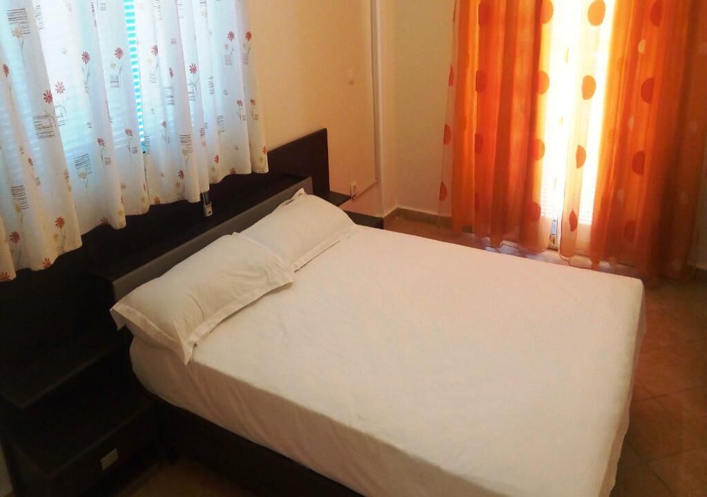 Un lit simple avec une literie blanche, dans une chambre dont la tête de lit est de couleur sombre.