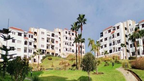 Un hotel moderno con varias edificaciones blancas, palmeras y un césped cuidado.