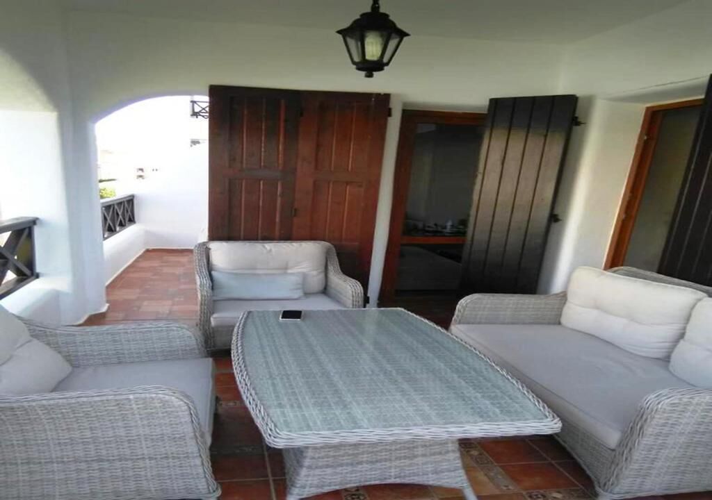 A balcony with wicker furniture, a table, and a wooden door.