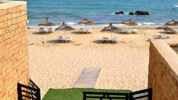 A beach with thatched umbrellas and white lounge chairs, a sandy shore, and a clear view of the ocean. - Residence Playa Del Pacha 4858 (Mdiq)