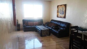 A living room with a wooden floor, two black leather sofas, a coffee table, and a dining table with chairs. - Residence Playa Del Pacha 1914 (Mdiq)
