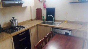 A compact kitchen with a gas stove, sink, and dishwasher. There is a wooden table and chairs. - Residence Playa Del Pacha 1914 (Mdiq)