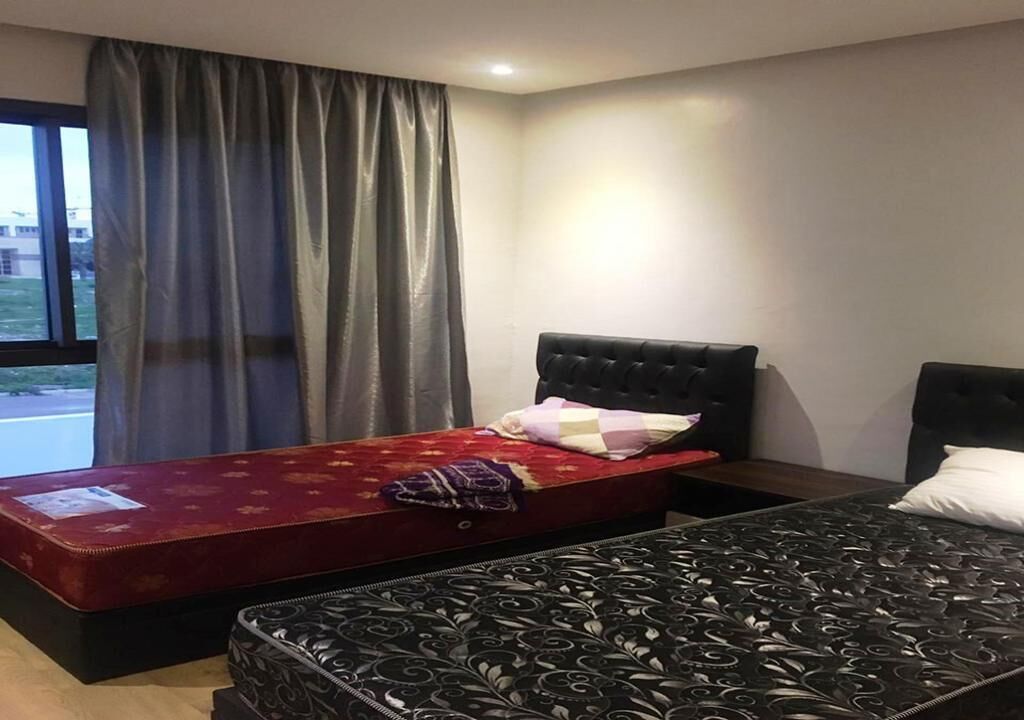 A hotel room with two beds, a window with curtains, and a view of the outside.
