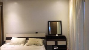 Quarto de hotel com uma cama, uma mesa de cabeceira com espelho e uma janela com cortinas.