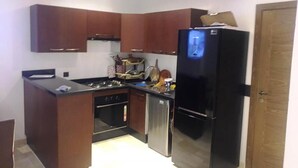 Uma cozinha compacta com armários de madeira escura, geladeira preta, fogão e lava-louças.