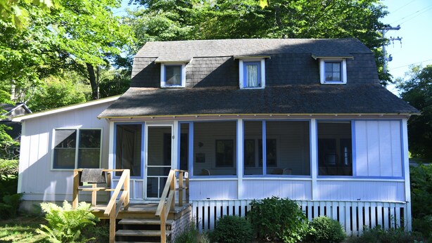 A two-story house with a porch, a front staircase, and a picket fence. - The Violet Cottage (Frankfort)
