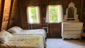 A cozy wooden cabin bedroom with two beds, a dresser, and a mirror. - The Violet Cottage (Frankfort)