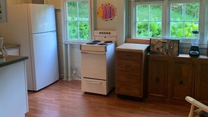 A kitchen with a refrigerator, stove, and wooden cabinets. - The Violet Cottage (Frankfort)