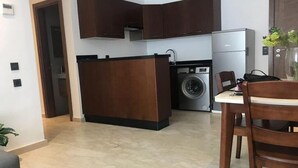 Una cocina compacta con armarios de madera oscura, lavadora y refrigerador.
