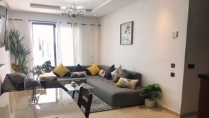 Una sala de estar moderna con un sofá modular, una mesa de comedor y una planta en maceta.