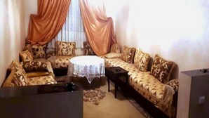 A living room with a sofa set, a coffee table, and a television. - Apartment El Farah 10 min from the beach 4622 (Agadir)