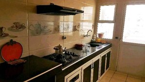 A kitchen with a stove, cabinets, and a window. - Apartment El Farah 10 min from the beach 4622 (Agadir)