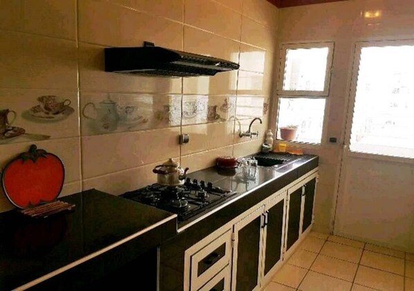 A kitchen with a stove, cabinets, and a window.