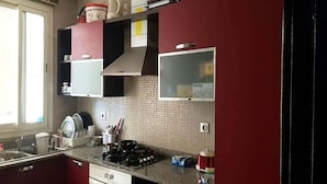 Een keuken met rode kastjes, een gasfornuis en een betegelde achterwand.