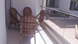 A balcony with wicker chairs and a glass railing, overlooking a building with multiple windows. - Residence Adan Beach 4724 (Aourir)