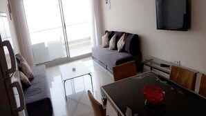 Een moderne woonkamer met een bank, een eettafel en een televisie.