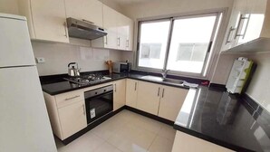 A kitchen with a stove, microwave, and sink.