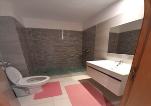 A bathroom with a toilet, sink, and shower area.