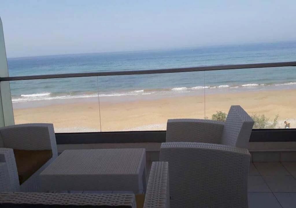 Varanda com mobiliário de vime branco com vista para a praia.