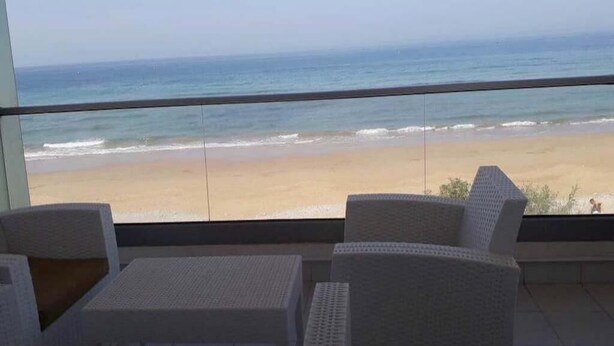 A balcony with white wicker furniture overlooking a beach. - Residence Adan Beach 4811 (Aourir)