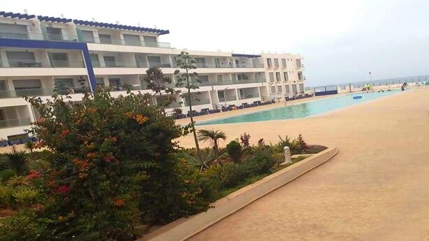 Ett hotell med pool, flera våningar och ett område med sandstrand.