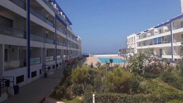A hotel with multiple floors, outdoor swimming pool, and lush greenery. - Residence Adan Beach 4786 (Aourir)
